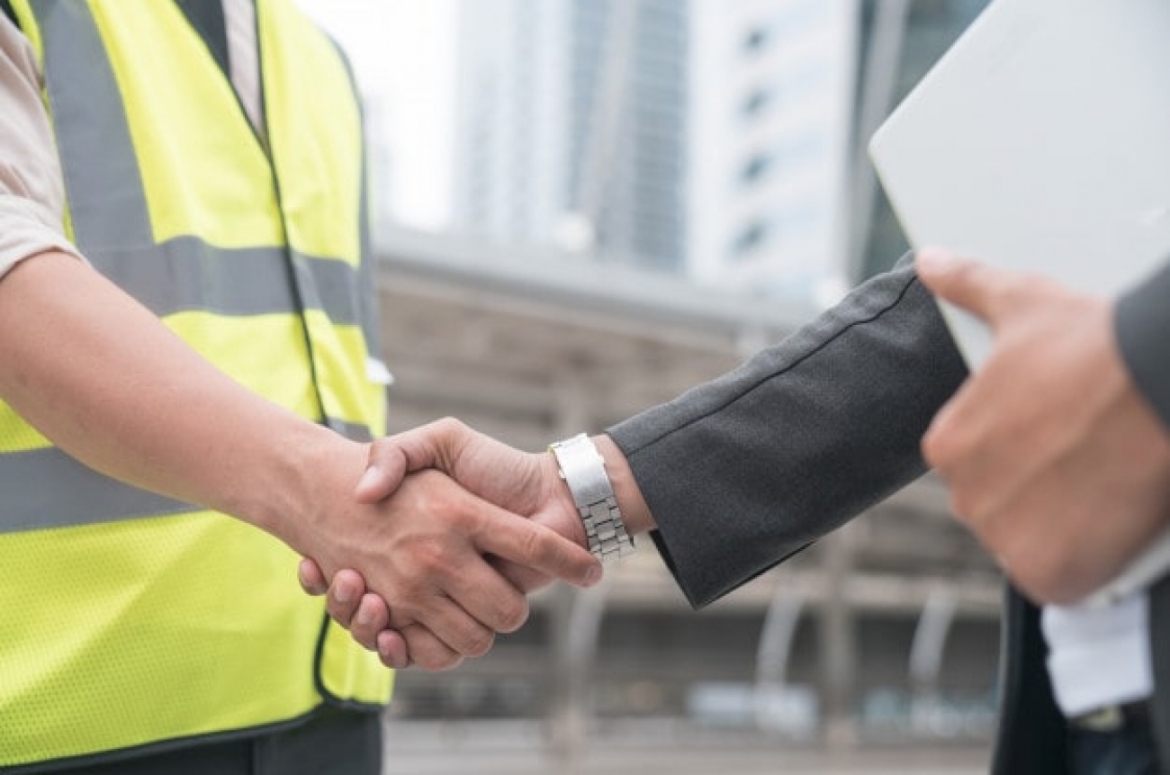 construction-workers-protective-helmets-vests-are-shaking-hands-while-working_35048-1443-min